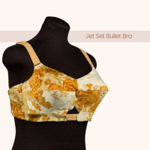 An angled front and side view of the Jet Set Bullet Bra Pattern in a an ivory and marigold floral patterned fabric with light yellow elastic on a black dress form with the text “Jet Set Bullet Bra”.