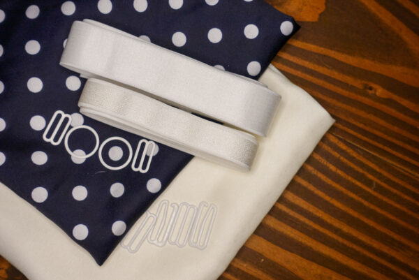 The Navy Polka Dot Satin Jet Set Kit features ivory polka dot pattern on navy satin fabric and a solid ivory satin fabric; white elastic; and white rings, g hooks, and sliders.