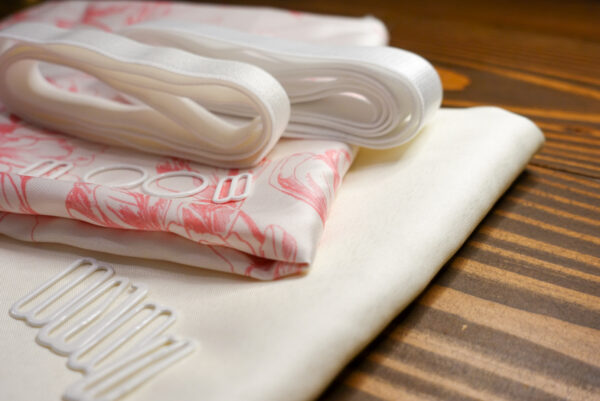 The Pink Floral Satin Jet Set Kit features a pink floral pattern on ivory satin fabric and a solid ivory satin fabric; white elastic; and white rings, g hooks, and sliders.