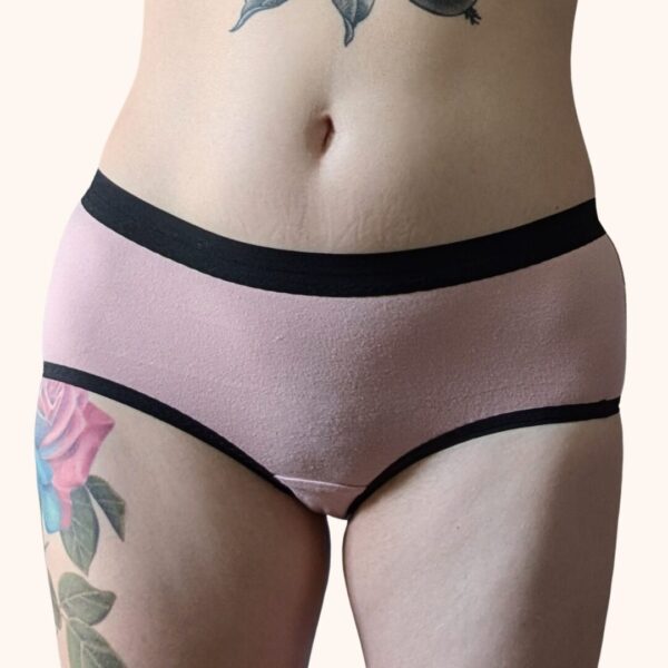 A front view of a model wearing the Constellation Panty Pattern in light pink fabric with black elastic.