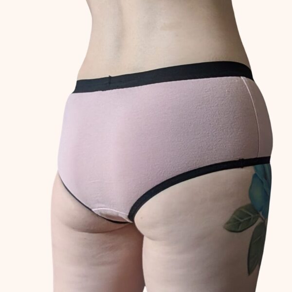 A back view of a model wearing the Constellation Panty Pattern in light pink fabric with black elastic.